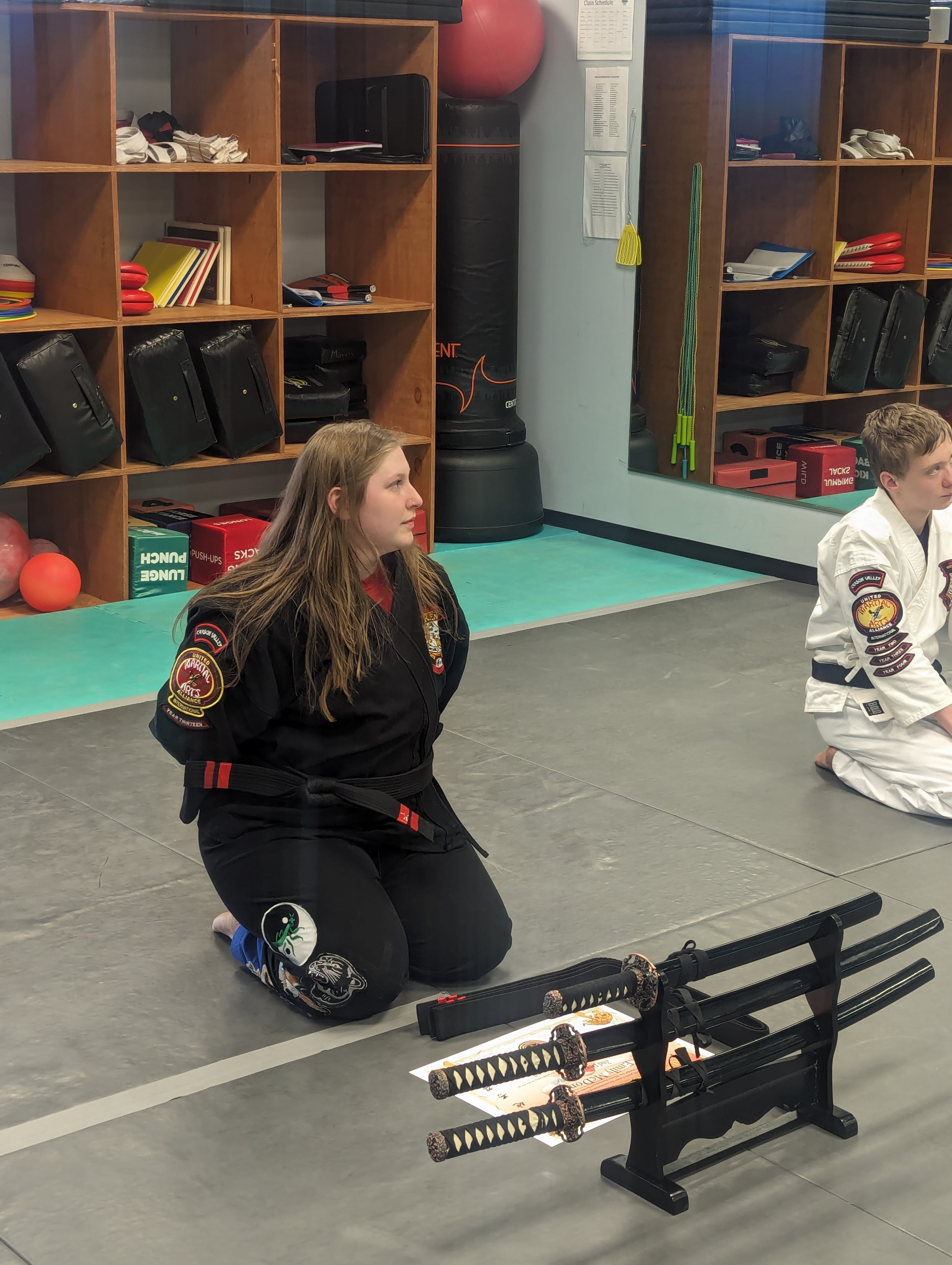 Teen student kneeling with traditional katana sword display