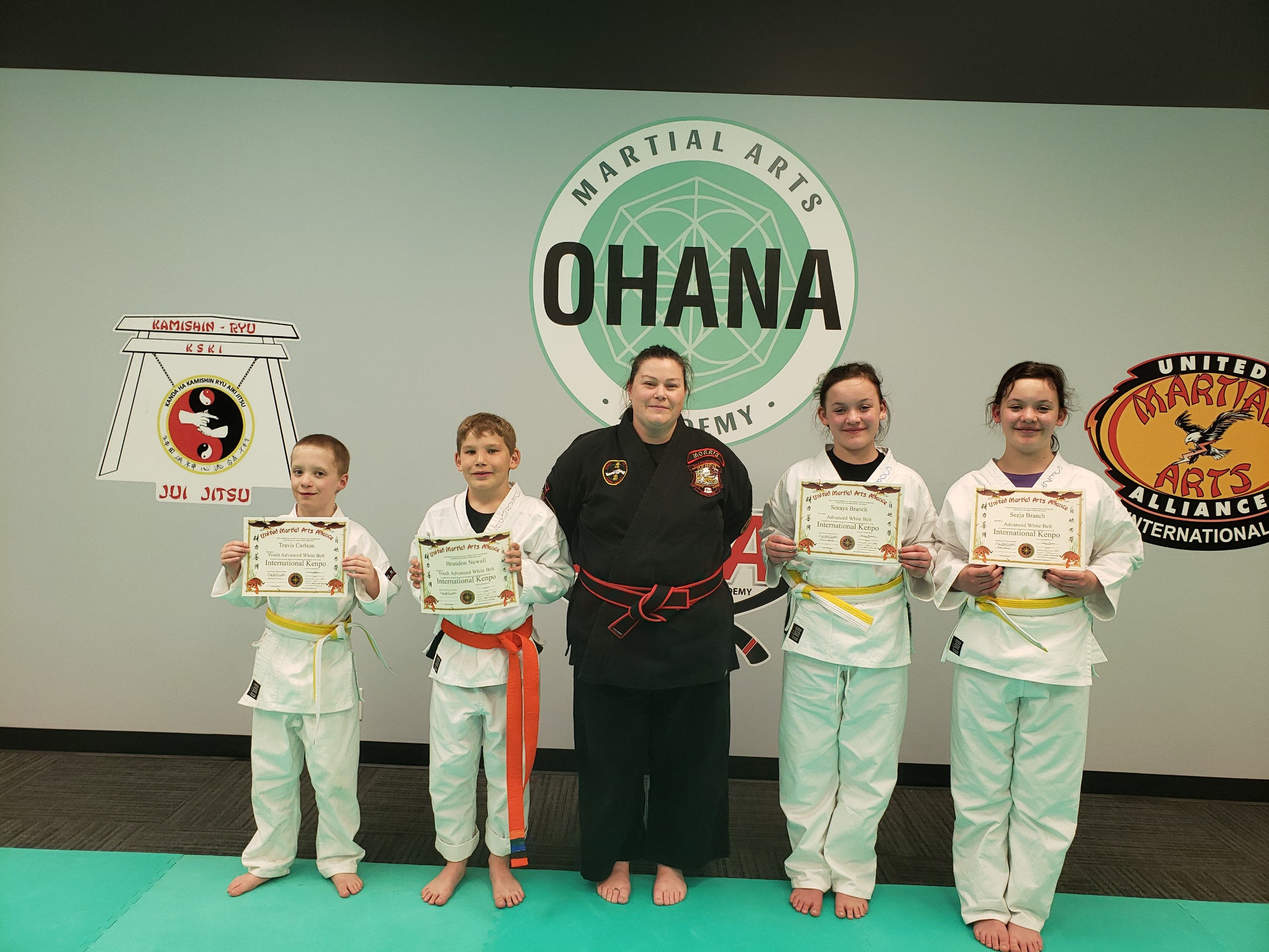Youth students with belt rank certificates and Sensei Carissa